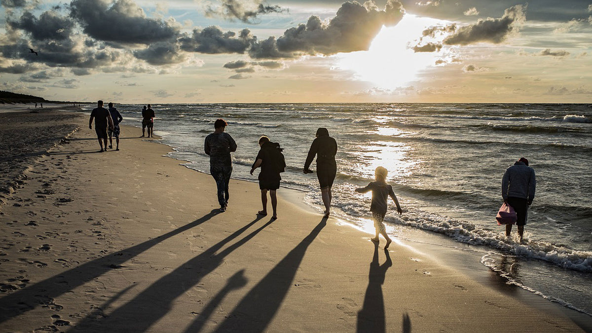 Family walking along the beach shoreline during sunset