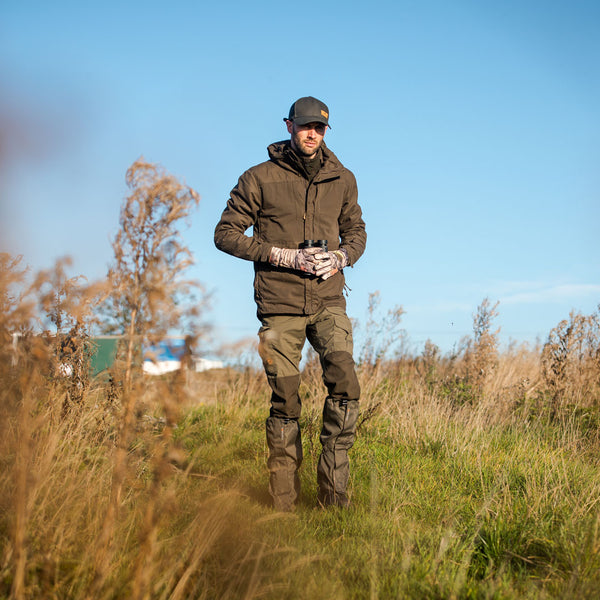 Lifestyle shot of a man wearing Extremities Field Gaiters in long grass