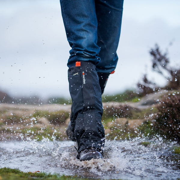 Lifestyle photograph of someone wearing Extremities GORE-TEX Nova Gaiters walking through a puddle with walking boots