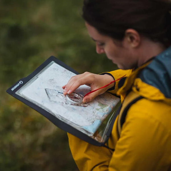 Woman using a map within a Lifeventure Waterproof Map Case with her compass whilst walking outdoors 