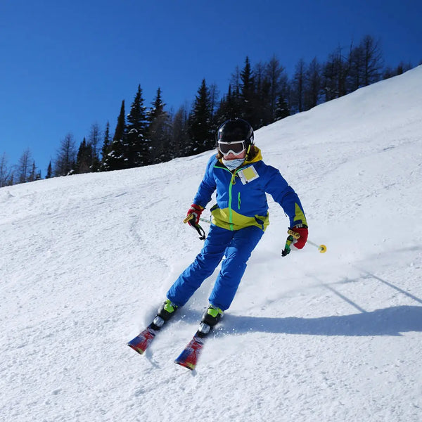 Man skiing down a snow slope whilst wearing a pair of Manbi thermal tube socks in dotty purple pattern