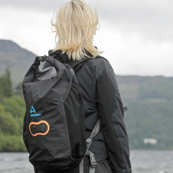 Aquapac wet and dry lightweight waterproof backpack being worn on the back of a woman looking out over a lake in winter