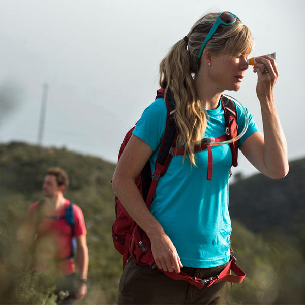 Lifestyle image of a woman applying Care Plus sun cream from teh slave stick to her nose whilst out hiking in the sun
