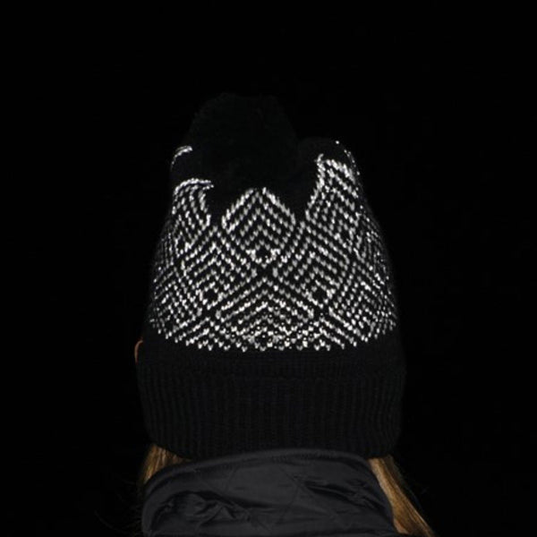 Lifestyle image of a person wearing an extremities Antares reflective thermal bobble hat in the dark and showing the yarn reflecting the torchlight 