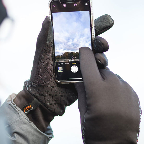 Lifestyle shot of someone wearing Extremities Waterproof Sticky Power Liner Gloves whilst using their smart phone