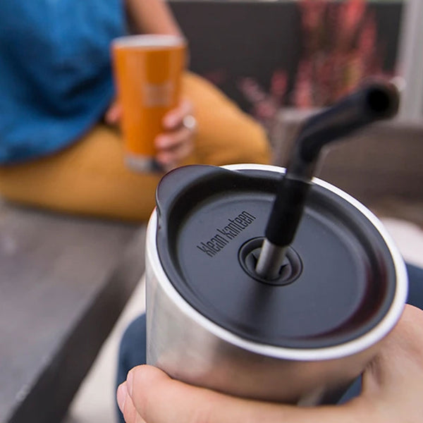 Lifestyle shot of a person holding a stainless steel pint tumbler using a tumbler straw lid in black