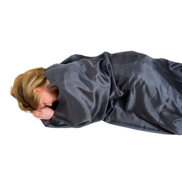 Woman asleep inside a Lifeventure silk sleeping bag liner in mummy shape on a white background