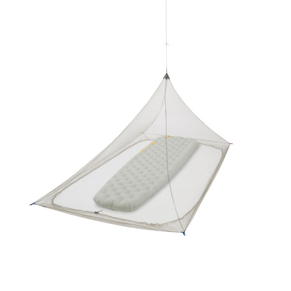 Studio shot on a white background of Sea To Summit Nano Pyramid single mosquito net suspended from the ceiling with a single inflatable mattress inside.